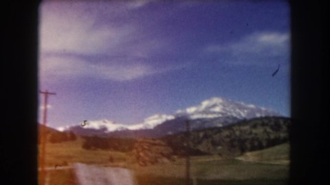 SUMMIT COUNTY COLORADO USA-1962: Moving Shot Of Large Snow Covered Mountain In The Distance With Telephone Poles In Foreground