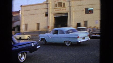 BARRINGTON ILLINOIS USA-1963: Cars Driving In A White 1950s Town Going By A Beige Building