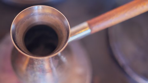 This video captures turkish coffee being prepared over a stove top, reaching a boiling point and spilling over the edges.