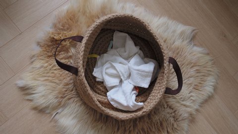 Top view - Stop Motion of guest towels are filling into a laundry basket on a floor. Cozy laundry basket with linen