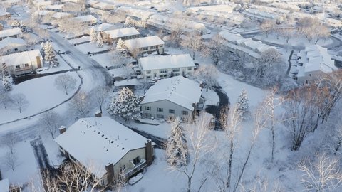 Aerial view of residential houses covered snow at winter season. Establishing shot of american neighborhood, suburb at wintertime.  Real estate, Midwest, sunny morning, soft sunlight. Drone shot 