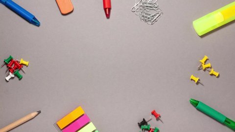 Pen, sticky note, marker, eraser, push pins, paperclip on gray background. Stop motion animation flat lay top view. Education and back to school concept.