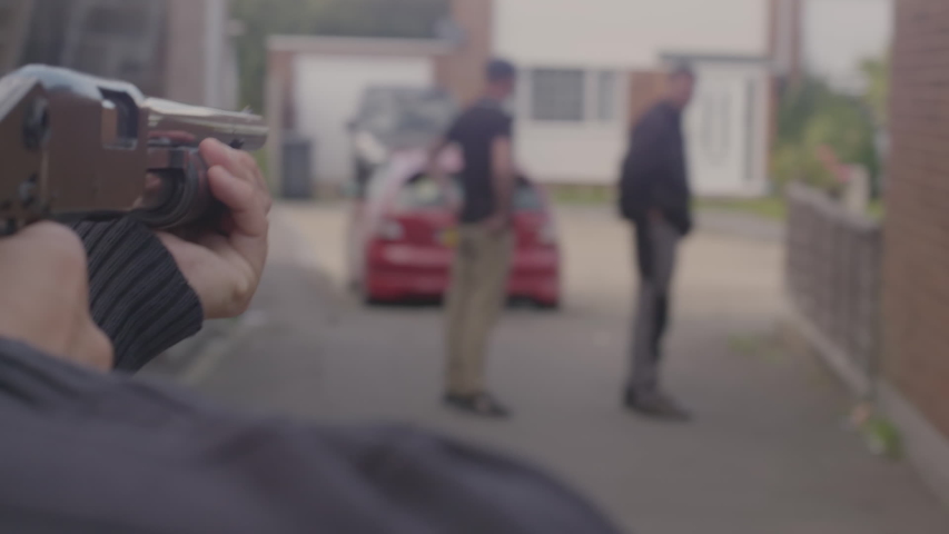 Over the shoulder view looking down the barrel of a shotgun being aimed at two people