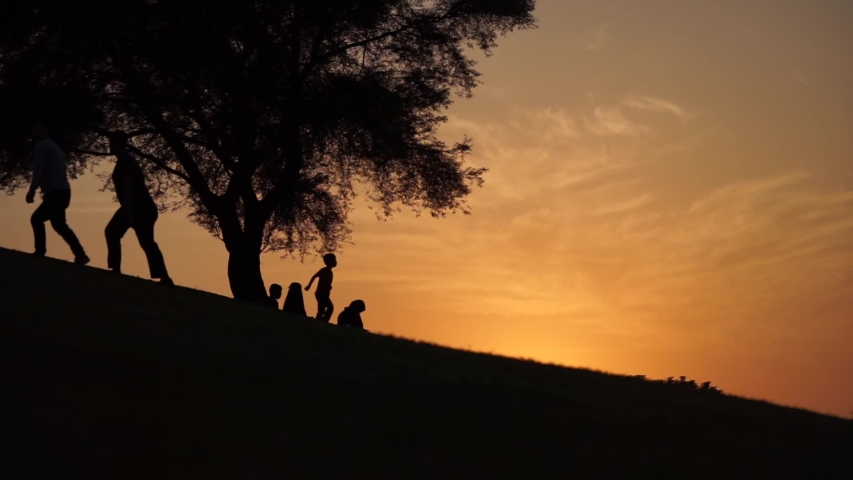 Silhouette of kid running downhill at sunset in slow motion