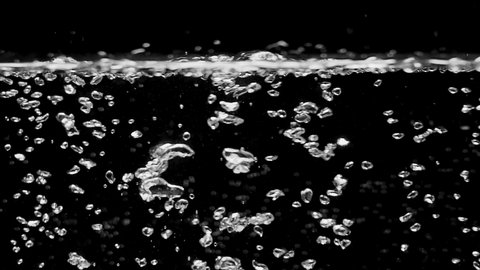 Bubbles rising up. Boiling water, closeup. Isolated black background. Shot on the cinema camera RED Dragon. UHD. 240 fps