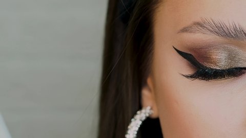 Glamorous bright eye makeup, women's eyes close-up. Bright party makeup, eye shadow and arrow eyeliner, trending eyebrows