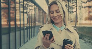 Attractive business woman smiling portrait. Young business people confident pretty. Female goes with smartphone in the city. Growing, success. 4K slow motion video
