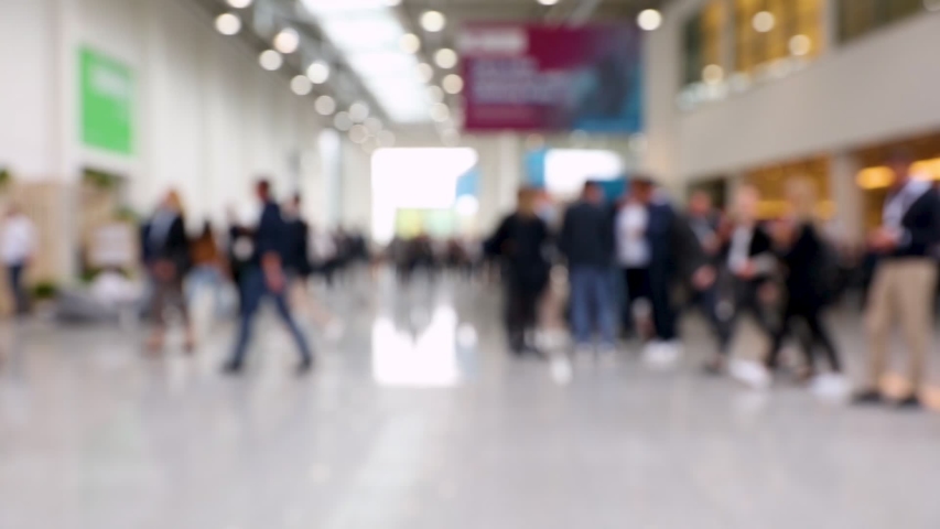Blurred crowd of people passing by at a convention in a conference hall (HD) Royalty-Free Stock Footage #1046311312