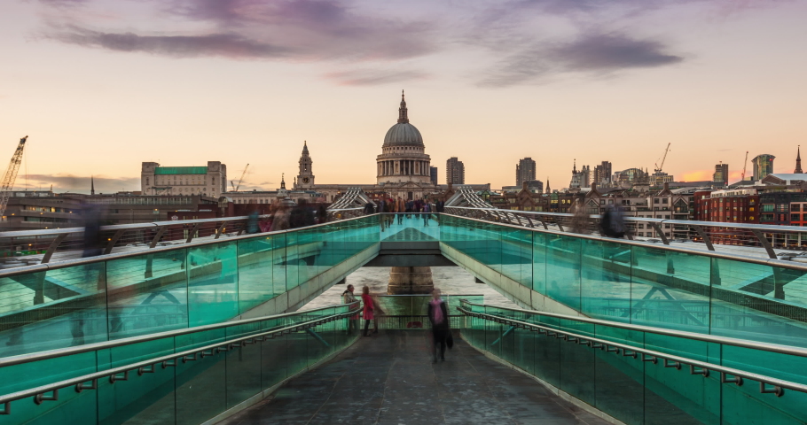 UHD Sunset timelapse of the Millennium bridge with St Paul cathedral and crowd of tourists and commuters walking in London, UK