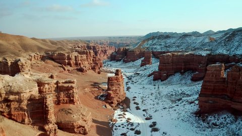Charyn canyon in cloudy weather. Dron view. Winter. National Park in Almaty, Kazakhstan. Orange rocks, blue sky. Giant natural amphitheaters and hoodoos formations.