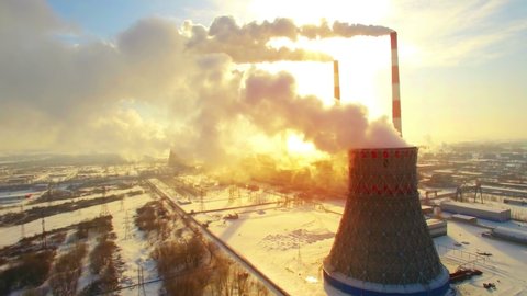 Aerial panoramic flight of hyperlaps around the thermal power plant. Winter carbon dioxide emissions, Energy of smoke and steam, sun shines through clouds of smoke. Ecology and pollution of nature.