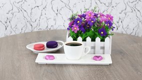 Coffee cup with flowers and macaroons on spinning wooden table background. FHD.