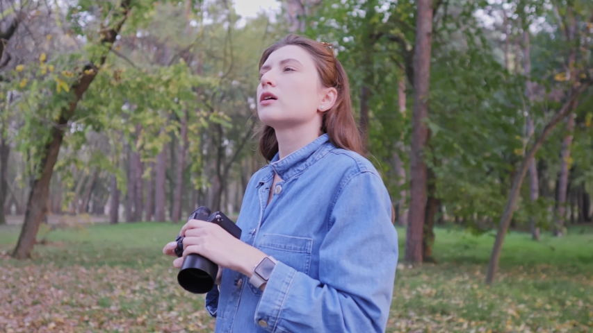 A professional photographer while working outdoors. Autumn Forest, Caucasian woman content creator