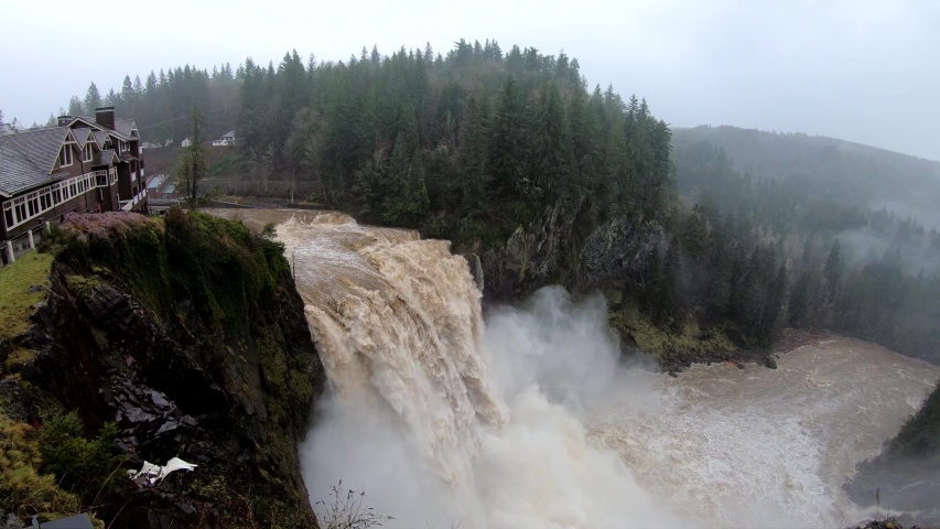 4K slow motion shot looking down on raging river at floodstage as it plunges over roaring waterfall at Snoqualmie Falls in the Pacific Northwest