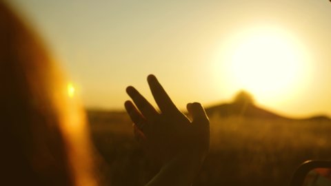 man traveler from the car window plays fingers with sunbeams. drivers hand is playing with sun from car window against beautiful sunset. Girl's hand waves sun. To travel by car