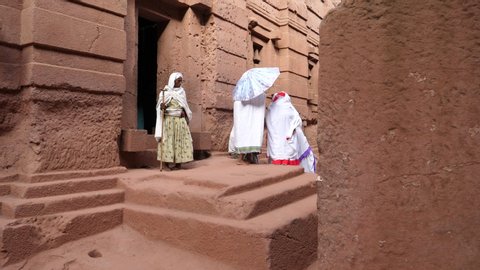Lalibela / Ethiopia - 11 12 2019: Ethiopian women walking out of monolithic church carved from stone in Lalibela