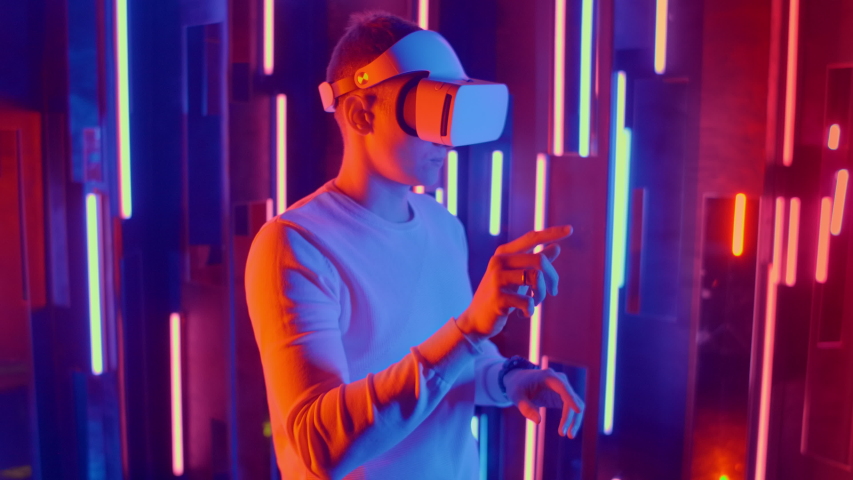 Young Man putting VR headset on the viewer in neon lights