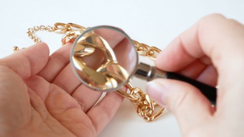 jeweler looking at jewelry through magnifying glass, jewerly inspect and verify