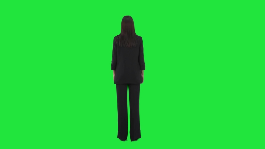 Back view of business woman in suit turning at camera and laughing. Full length on green screen background.