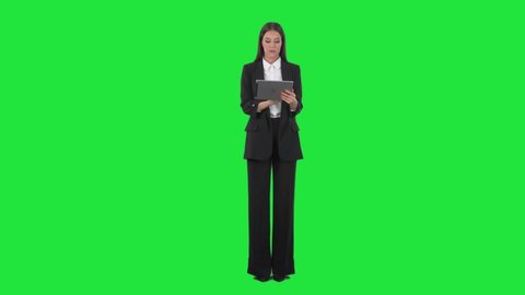 Serious busy young business woman using tablet computer interacting with touch screen. Full length on green screen background.