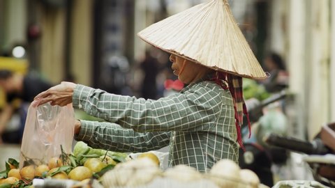 Handheld view of Vietnamese woman selling fruit at the market. Shot with RED helium camera in 8K