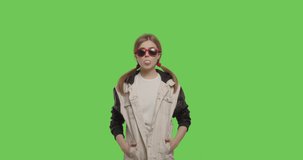 Young pretty girl wearing jacket chewing bubble gum over green screen background, Woman in sunglasses having fun on chroma Key . 4k raw video footage slow motion 60 fps