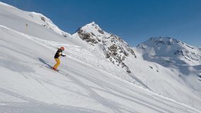 4K skiing footage, one woman skilled skier skiing on ski slope in dynamic short turns on sunny winter vacation day with clear blue sky high up in european alps mountains, side view, tracking shot
