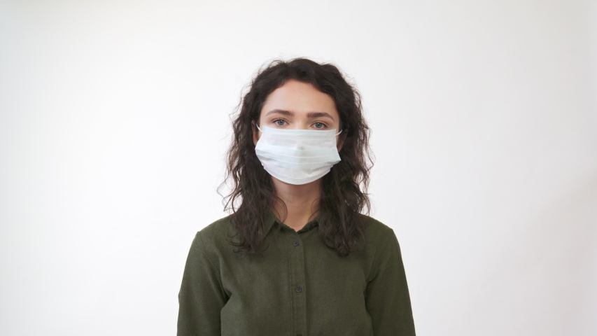 Young woman takes off medical mask. Female breathes deeply and smiling looking at camera. Isolated on white  background. Health care and medical concept. Close up portrait . 4k | Shutterstock HD Video #1046403217