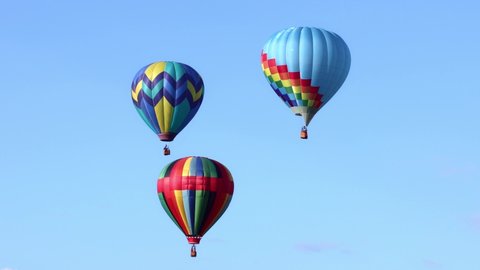 Three colorful hot air balloons on clear blue sky 