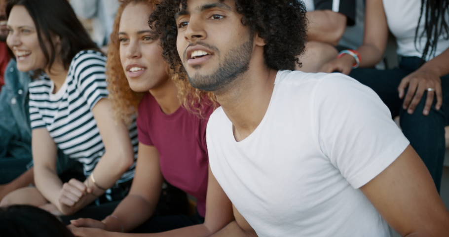 Young couple watching a sport event, jumping with hands raised, giving each other high five and hugging. Excited crowd of sports fans applauding and celebrating their team's victory.  Royalty-Free Stock Footage #1046414524