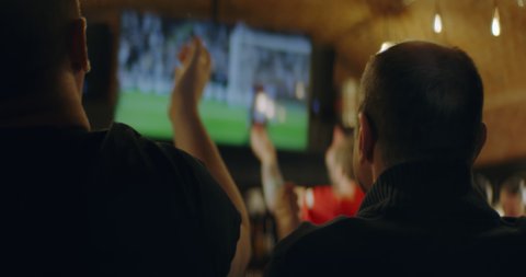 HANDHELD Model released, fans watching a game on a large TV in a sport pub. Shot on ARRI Alexa Mini with Atlas Orion 2x Anamorphic lens