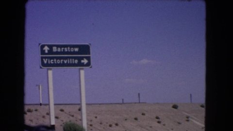 CALIFORNIA USA-1966: Film From Vehicle As It Drives Past A Road Sign Giving Directions To Barstow And Victorville