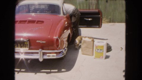 BARSTOW CALIFORNIA USA-1966: A Puppy Wiggling Its Tail Near Its Owner And Their Car