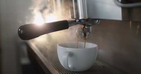 Making a cup of strong coffee in a coffee machine, the back light illuminates the steam and the cup.