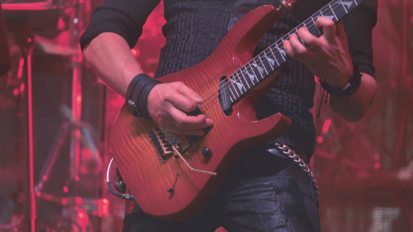 A virtuoso guitarist playing an electric guitar on stage with flashing LED lights. Royalty-Free Stock Footage #1046433445