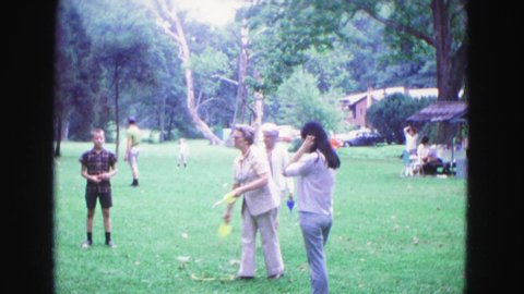 GALENA ILLINOIS USA-1967: Small Group Playing Tossing Game In Park Surrounded By Others Enjoying Area