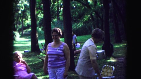 GALENA ILLINOIS USA-1967: Group Of People Having A Picnic In A Public Park As Kids Walk Around Holding Balloons