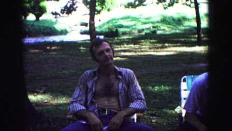 GALENA ILLINOIS USA-1967: Man In Unbuttoned Shirt And Jeans Talking At A Picnic