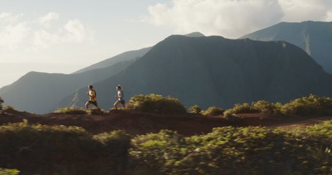 Aerial view of two adventurous ultra runners training for a marathon in the mountains, athletic couple exploring the great outdoors together