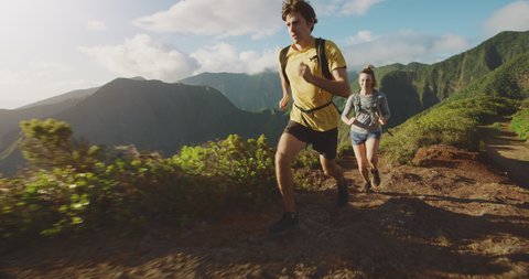 Young adventurous man and woman running on top of green mountains, trail runners running on epic mountain ridge, ultra marathon training, fun outdoor activities
