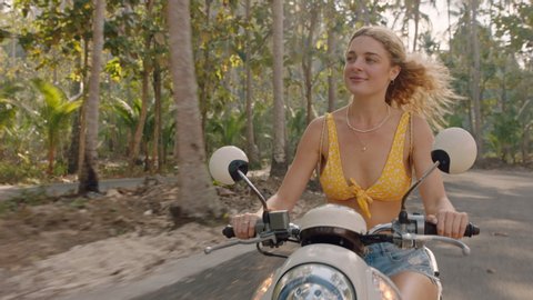 beautiful woman riding scooter on tropical island road trip enjoying motorcycle ride exploring freedom on vacation วิดีโอสต็อก