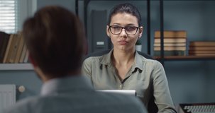 Concentrated woman with dark hair in grey blouse and eyeglasses discussing with male patient his excitements. Middle-aged man visiting professional therapist to deal with personal problems