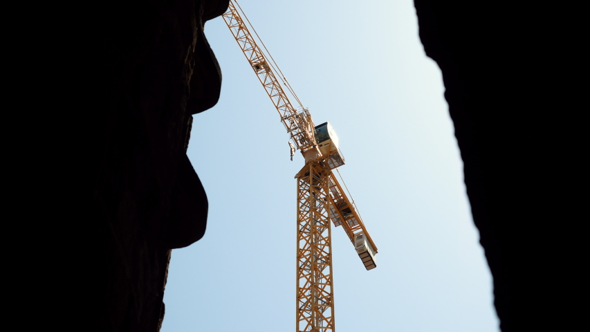 High crane is on construction site against blue sky on summer day. 4K