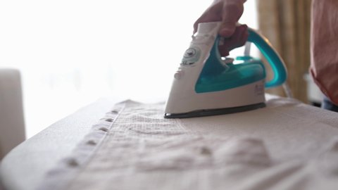 Male hands ironing clothes with iron on ironing board. slow motion