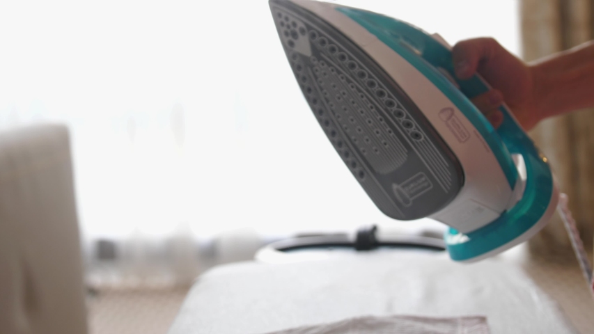 Close up of male hands ironing clothes with iron on an ironing board. slow motion | Shutterstock HD Video #1046454958