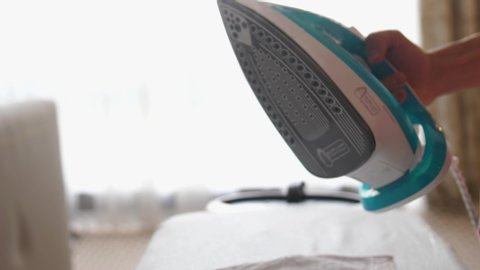 Close up of male hands ironing clothes with iron on an ironing board. slow motion