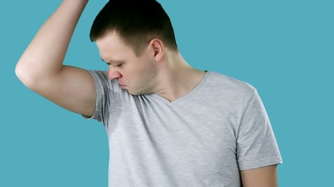 Young man sniffing his armpit, something stinks very bad. Bad smells concept.