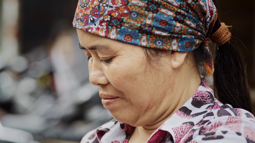 Handheld view of Vietnamese mature woman at the street market. Shot with RED helium camera in 8K
