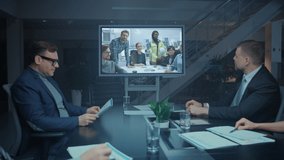 Late at Night Diverse Group of Executives and Management in the Meeting Room, Have Conference Video Call with Team of Engineers, Production Line Specialists. Optimizing Company Production and Growth