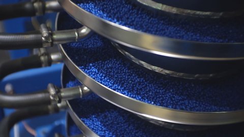 Processing of polymeric materials. Moving blue granules in production. Technological progress.